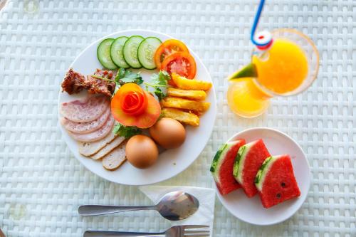 a table with two plates of food with eggs and fruit at Tre Xanh Hotel in Pleiku