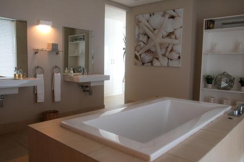 La salle de bains est pourvue d'une grande baignoire blanche et de 2 lavabos. dans l'établissement 25 Sovereign Sands, à KwaDukuza