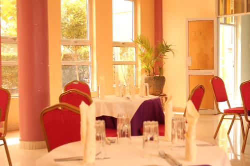 a dining room with a table and chairs and windows at Agenda 2000 Hotels Ltd in Kampala
