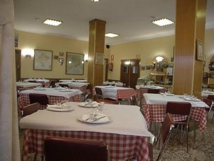 a restaurant with rows of tables and chairs with white tablecloths at Hostal Oasis in Fraga