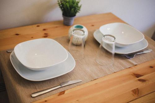 a wooden table with white plates and glasses on it at Smart Urban Orio in Orio