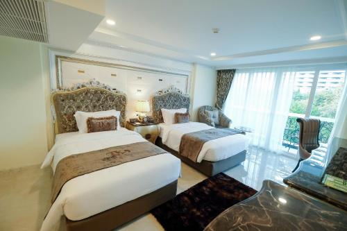 a hotel room with two beds and a large window at LK Emerald Beach - SHA Extra Plus in Pattaya North