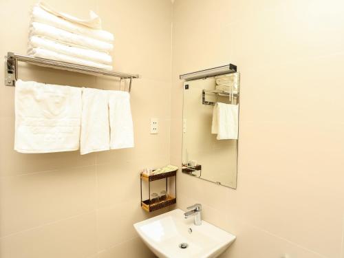 a bathroom with a sink and a mirror and towels at Hacom Galaxy Hotel in Phan Rang