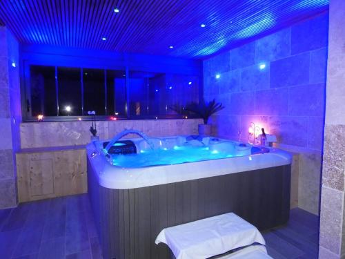 La salle de bains est pourvue d'une grande baignoire avec un éclairage bleu. dans l'établissement Charme et Spa dans un domaine d'élevage, à Sennevières
