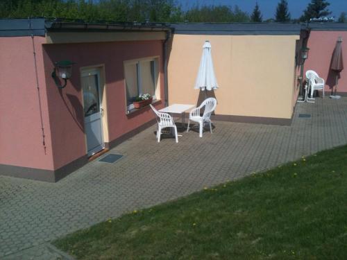 a patio with a table and an umbrella and chairs at Hotel-Pension Am Mühlberg in Lübbenau