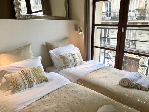two beds sitting in a room with a window at Appartement cœur de la bastille in Paris