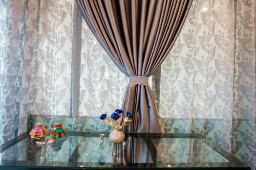 a glass table with a curtain on a window at Dalat Terrasse Des Roses Villa in Da Lat