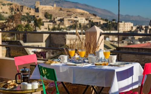 een tafel met eten en glazen sinaasappelsap op een balkon bij La Maison Maure in Fès