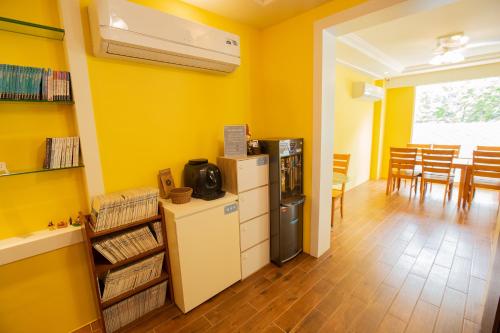 uma cozinha com paredes amarelas e um frigorífico num quarto em Songhe ShanShuei B&B em Heping