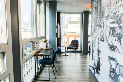 a hallway with blue walls and windows and blue chairs at The Verdandi Hotel in Oslo