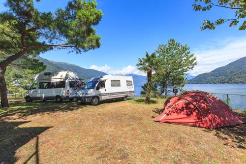 two rvs and a tent next to a lake at Lakeview Cannobio Camping & Resort in Cannobio
