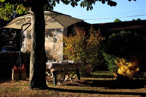 a table and chairs under an umbrella in a yard at Au Relais de Nèche. in Bègues