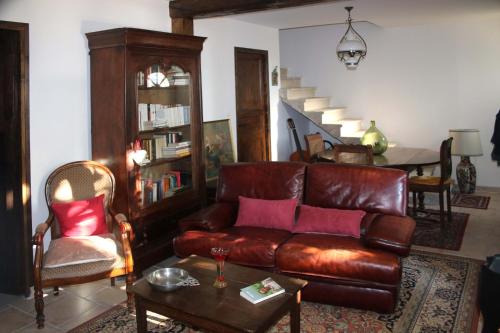 a living room with a leather couch and a table at Au Relais de Nèche. in Bègues