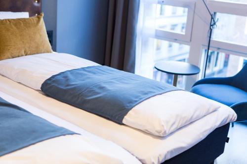 a bed with a blue and white pillow and a chair at The Verdandi Hotel in Oslo