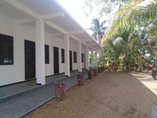 een gebouw met een rij ramen en palmbomen bij Quench Inn in Ampara