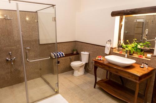 a bathroom with a shower and a sink and a toilet at Tranquil Resort - Blusalzz Collection, Wayanad - Kerala in Ambalavayal