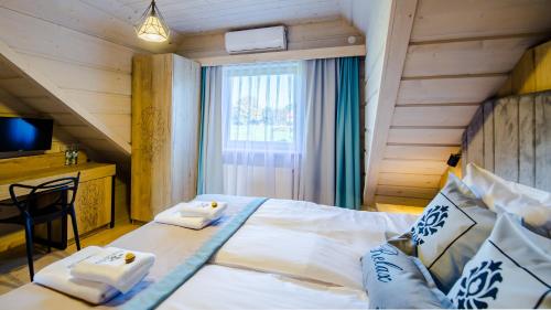 a bedroom with a large bed with two towels at Skansen Holiday in Cholerzyn