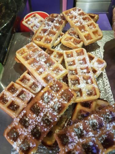 巴黎Hotel PARIS GAMBETTA- PANAMHOTEL-PERE LACHAISE的托盘上堆着一盘华夫饼，上面撒着糖粉。
