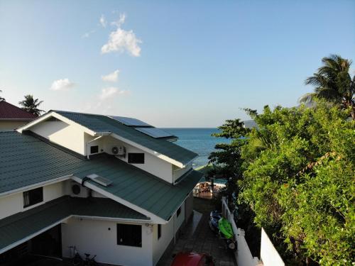 a house with a green roof and the ocean at The Drake Seaside Apartment in Bel Ombre