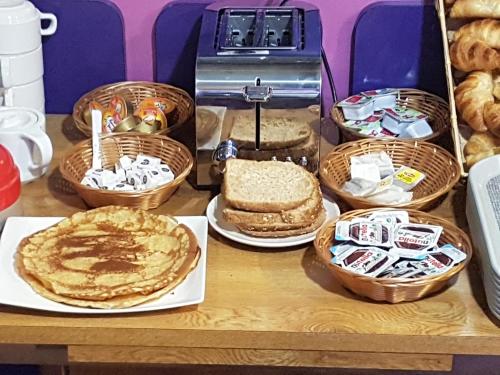 巴黎Hotel PARIS GAMBETTA- PANAMHOTEL-PERE LACHAISE的一张桌子,上面有面包和糕点篮子