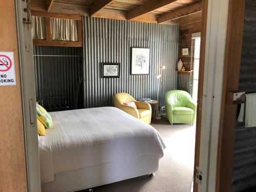 a bedroom with a bed and two chairs and a table at Bed in a Shed Vineyard Stay in Watervale