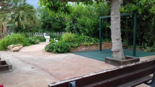 a park with a tree and a bench and a fence at Les Casetes de Camarles in Camarles