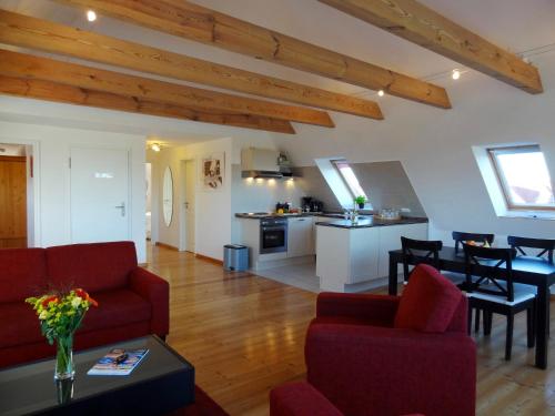 uma sala de estar com sofás vermelhos e uma cozinha em Ferienwohnungen Hass - Haus 10 em Fehmarn