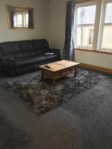 a living room with a couch and a coffee table at 3 coach house balnagown in Tain