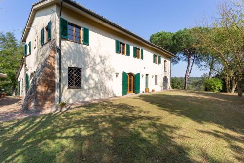 a large white building with green doors and a yard at Podere Le Capannucce in Pontedera
