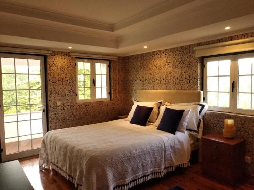 a bedroom with a large bed and two windows at Quinta da Telheira in Vila Real