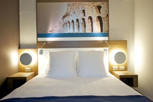 a bedroom with a bed with a painting on the wall at Mercure Roma Centro Colosseo in Rome