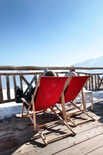 a red chair sitting on top of a deck at Hamilton Lodge & Spa in Belalp