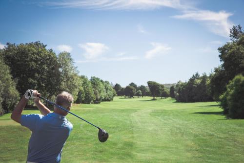 a man swinging a golf club on a golf course at Lanhydrock Hotel & Golf Club in Bodmin