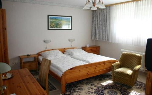 ein Schlafzimmer mit einem Bett, einem Tisch und einem Stuhl in der Unterkunft Pension Haus zum Schlehenberg in Bayreuth