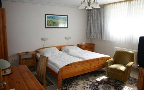 a bedroom with a bed and a table and a chair at Pension Haus zum Schlehenberg in Bayreuth