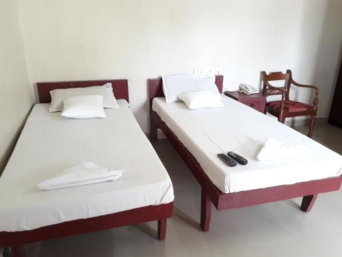 two beds in a room with a chair and a table at Marwa Inn in Trivandrum