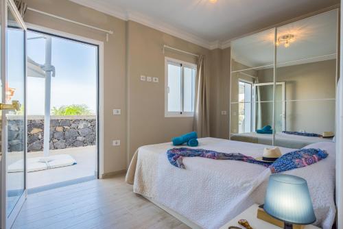 a bedroom with a bed and a large mirror at LUXURY WHITE VILLA with sea view, heated pool in Adeje