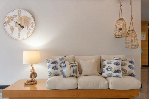 a living room with a white couch and a clock on the wall at The Navigator - Solaqua in Albufeira