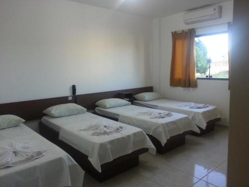 a room with three beds and a window at Hotel Sarandi in Foz do Iguaçu