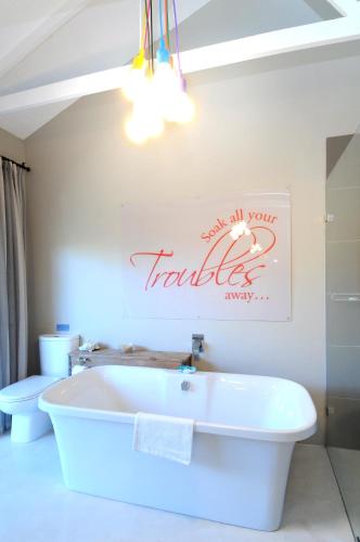 a bathroom with a white tub and a sign on the wall at Ocean Breeze by The Oyster Collection in Kenton on Sea