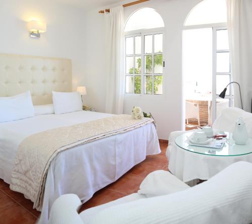 een witte slaapkamer met 2 bedden en een tafel bij Hotel Casa Rosa in Benalmádena