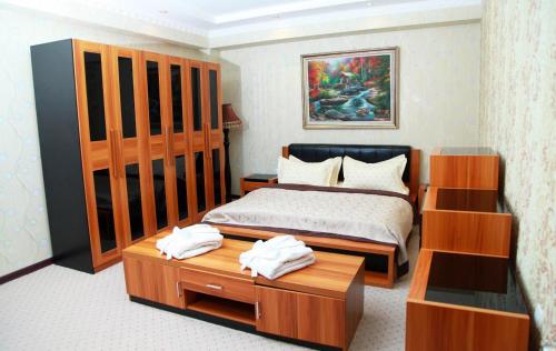 1 dormitorio con 1 cama y 1 mesa con toallas en Zarafshan Grand Hotel FIEZ, en Malik