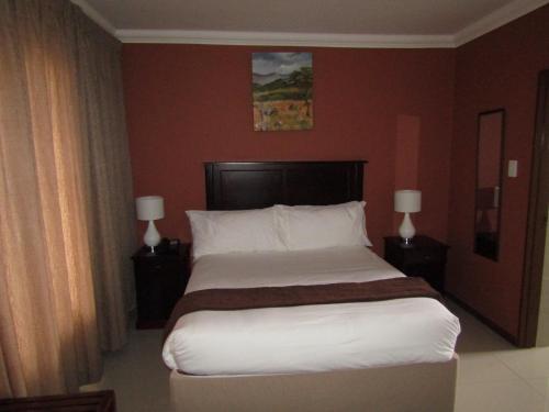 a large bed in a hotel room with two lamps at Vido Lodge and Conference Centre in Polokwane