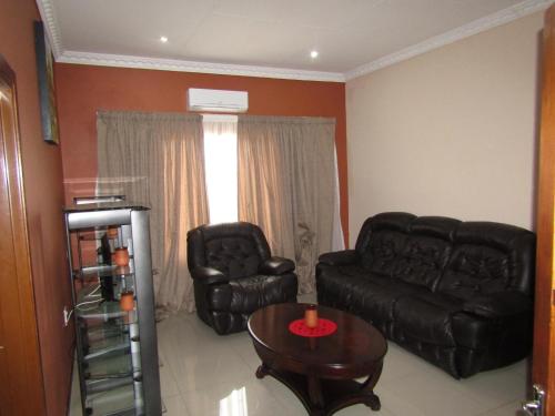 a living room with a black leather couch and a table at Vido Lodge and Conference Centre in Polokwane