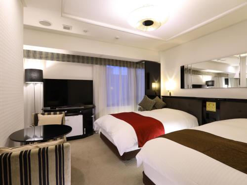 ein Hotelzimmer mit 2 Betten und einem Flachbild-TV in der Unterkunft APA Hotel Tokyo Kudanshita in Tokio