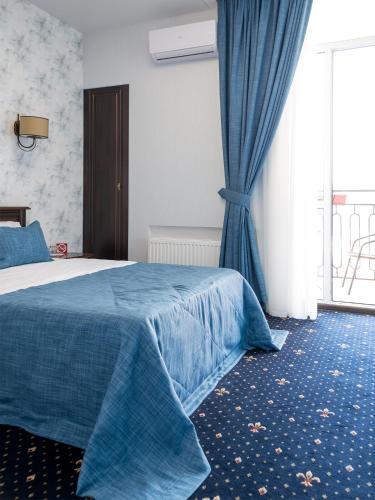 a bedroom with a bed with a blue blanket and a window at ArcadiaSky in Odesa
