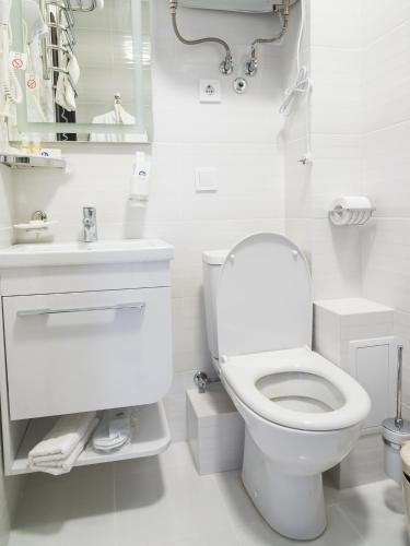 a white bathroom with a toilet and a sink at ArcadiaSky in Odesa