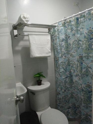 a bathroom with a toilet and a shower curtain with a plant at Cloud 907 Cityscapes Condominium in Bacolod