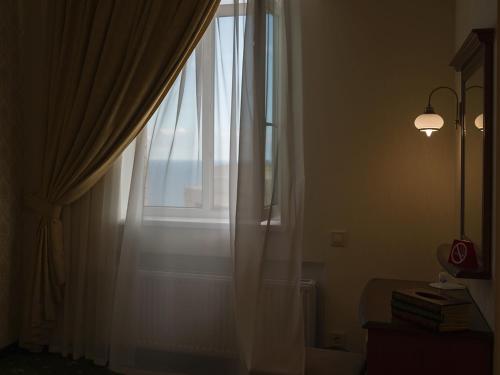 uma janela com cortinas brancas, um candeeiro e livros em ArcadiaSky em Odessa