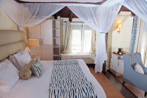 a bedroom with a bed with a canopy and a window at The Great Rift Valley Lodge & Golf Resort in Naivasha